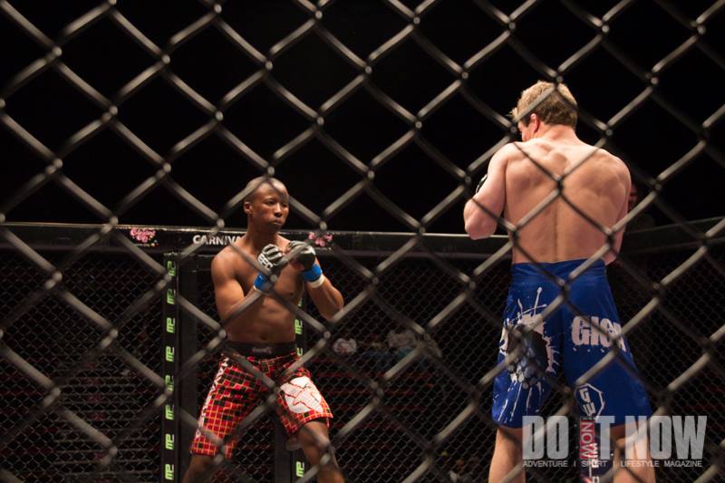 Two fighters facing each other through the arena cage