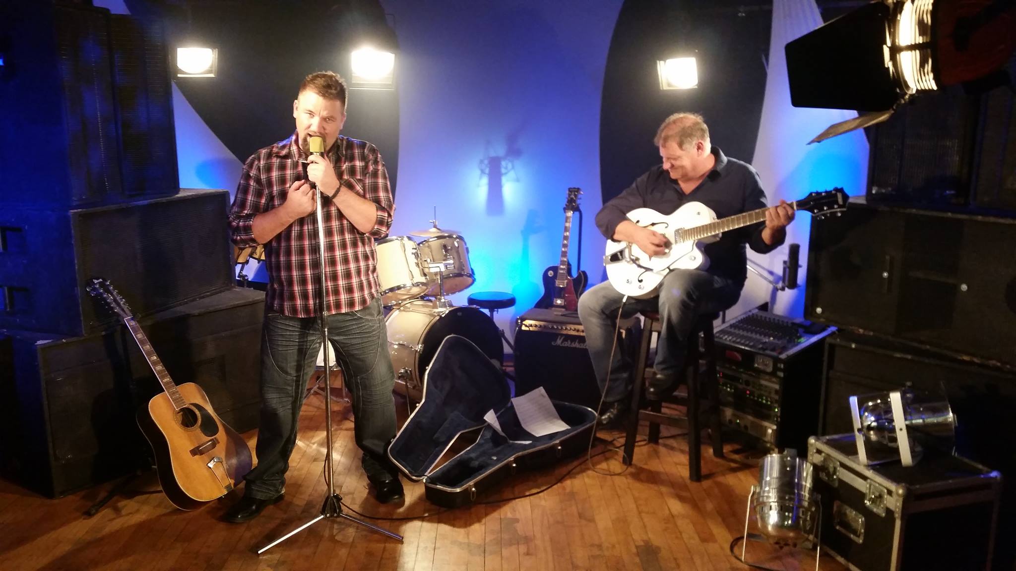 Presenter and guitarist performing under studio lighting